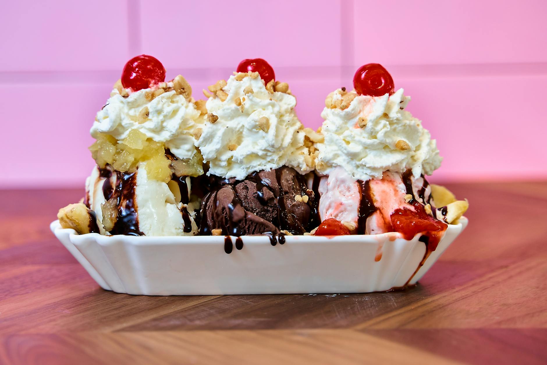 Deser banana split z bitą śmietaną, wiśniami i polewą czekoladową