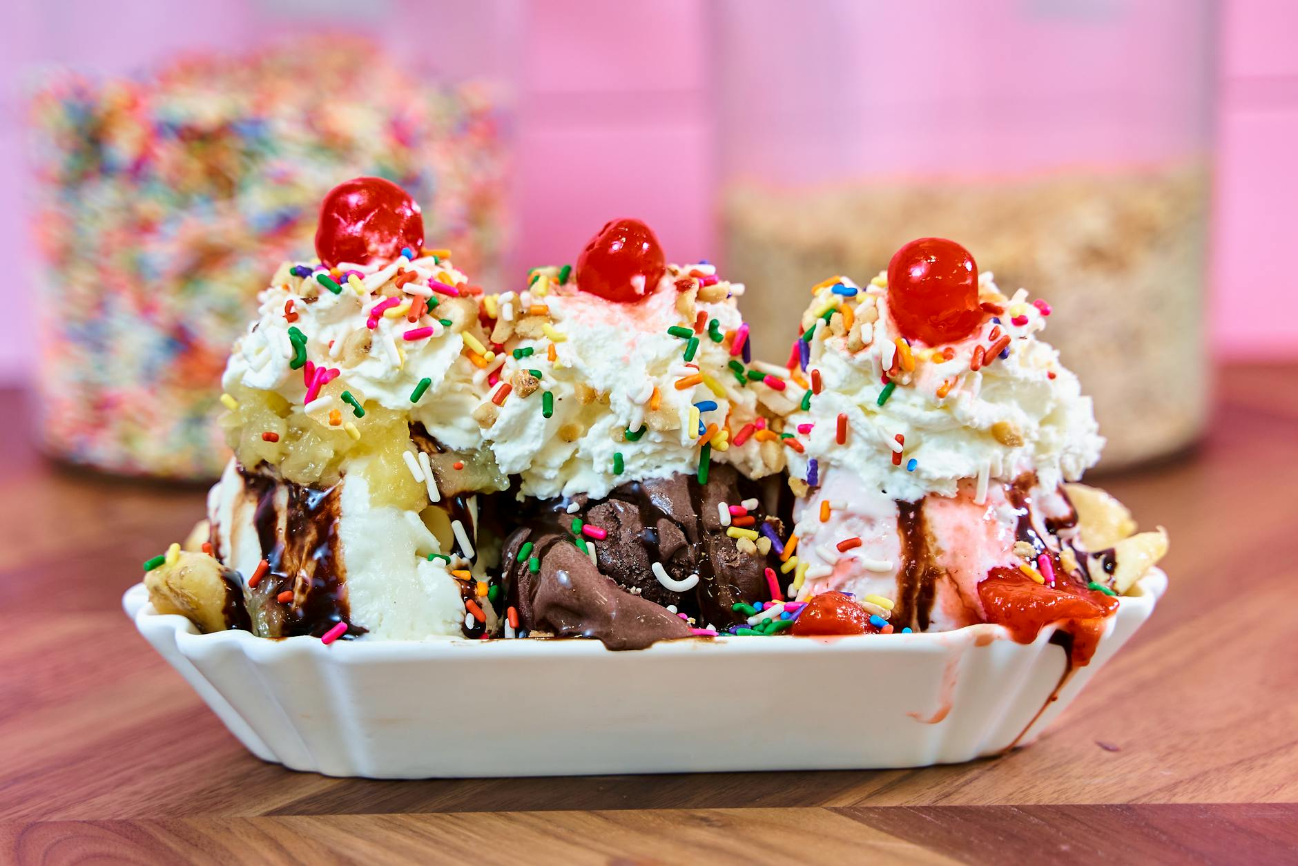 Kolorowy banana split z lodami, bitą śmietaną, wisienkami i posypką