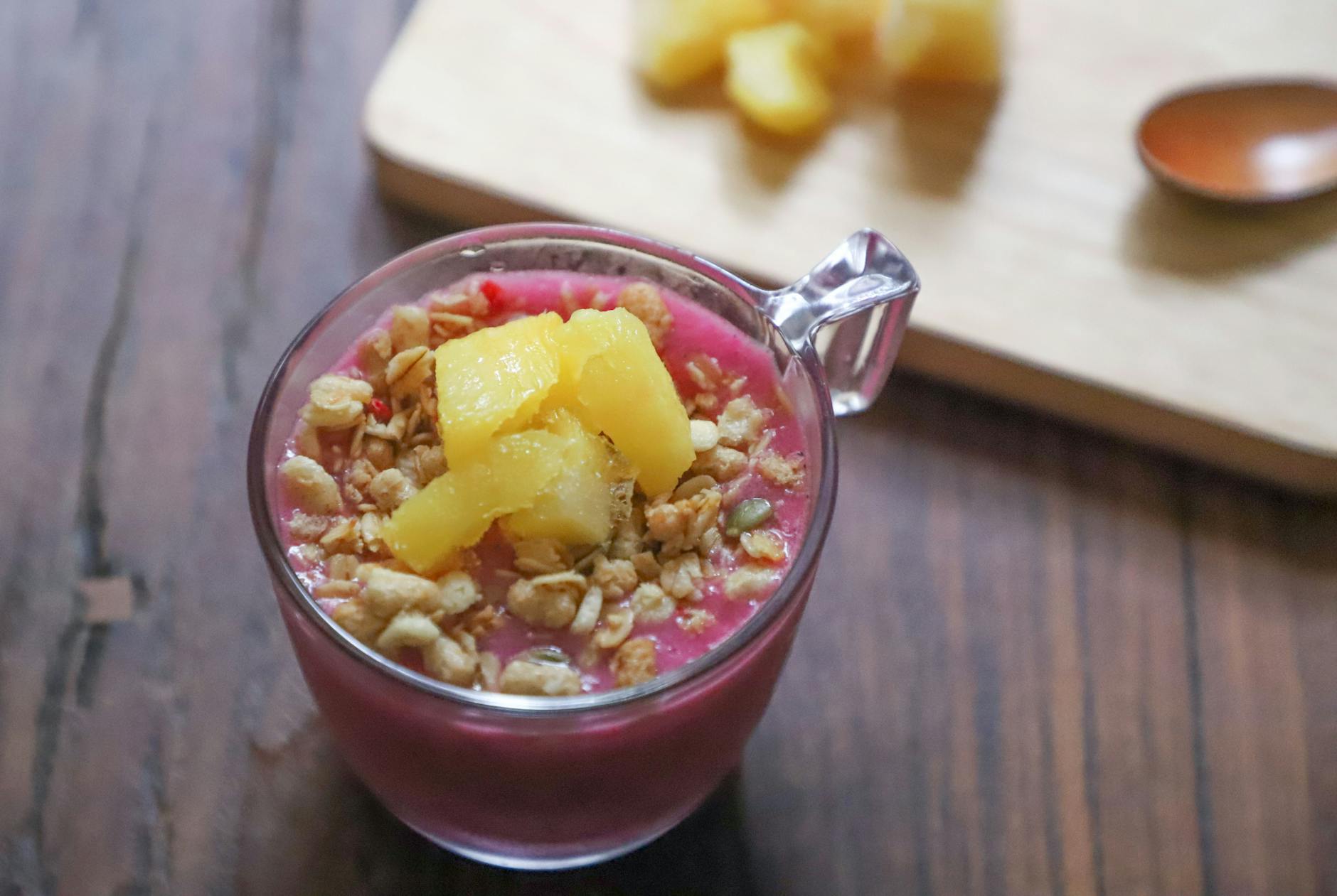 Miseczka smoothie z ananasem i granolą na drewnianym stole