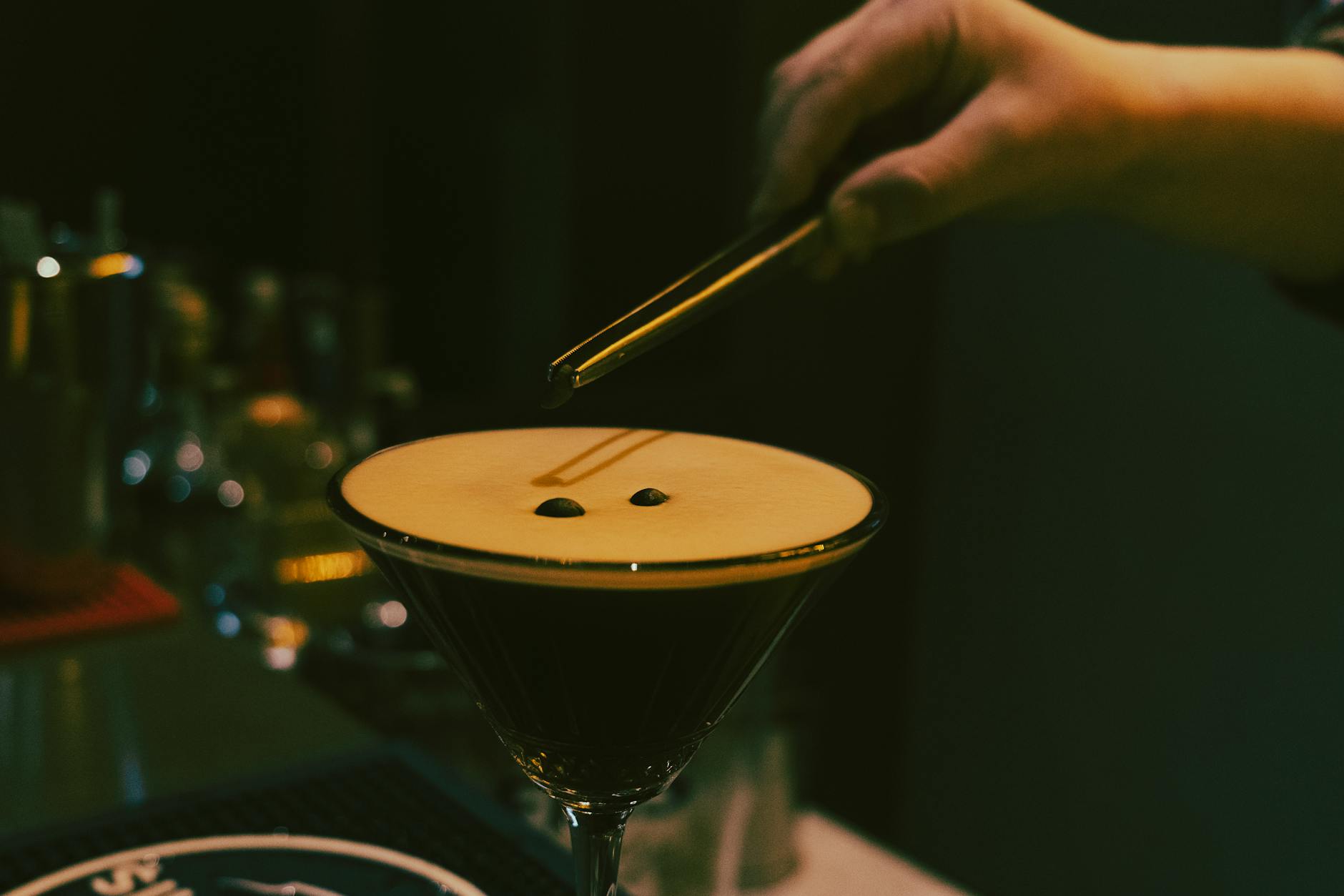 Barman przygotowuje bezalkoholowe espresso martini, dekorując je ziarnami kawy