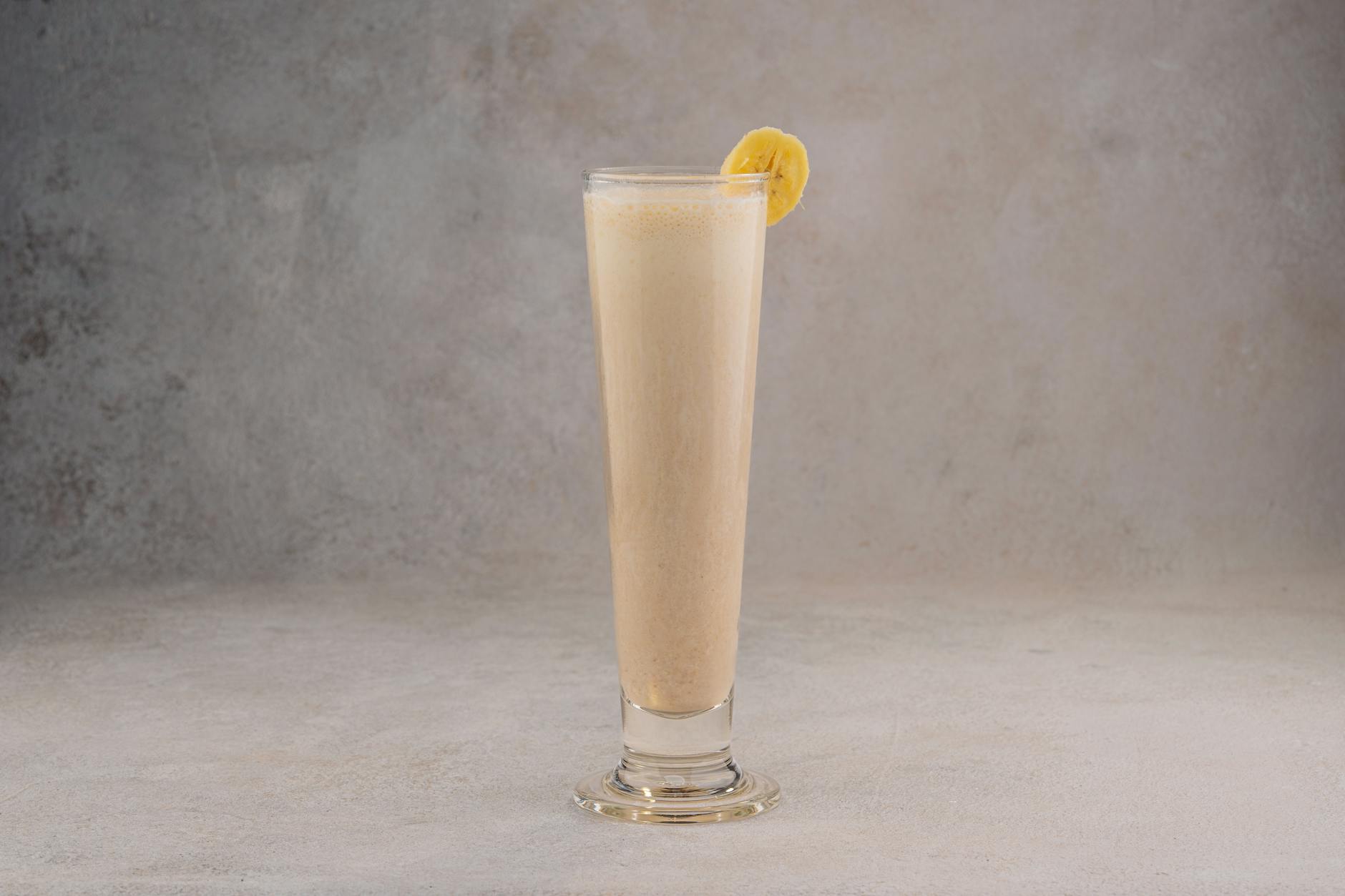 Szklanka bananowego smoothie kawowego z plastrem banana na brzegu