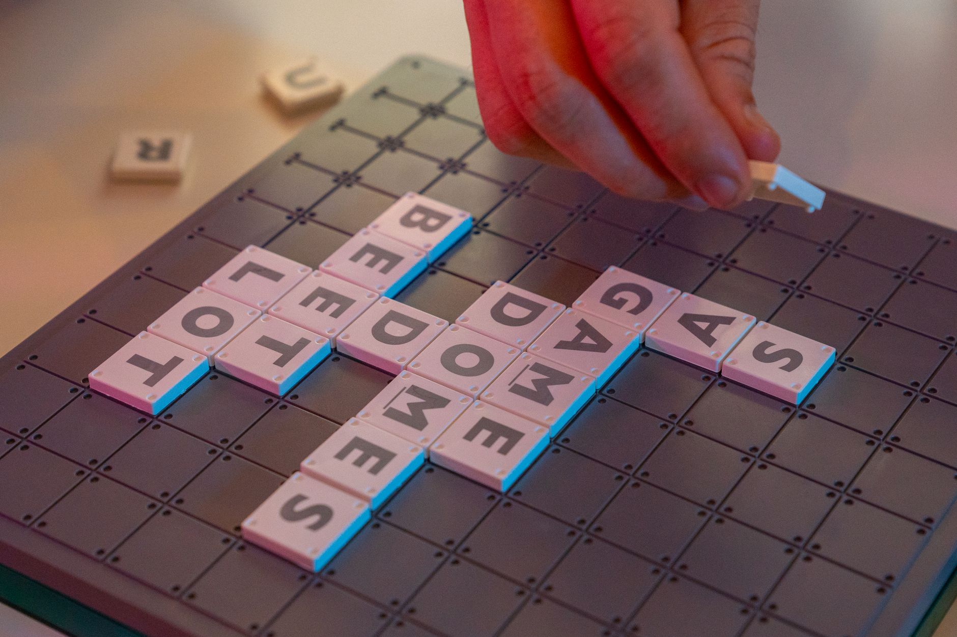 Dłoń układająca litery na planszy do Scrabble z bliska
