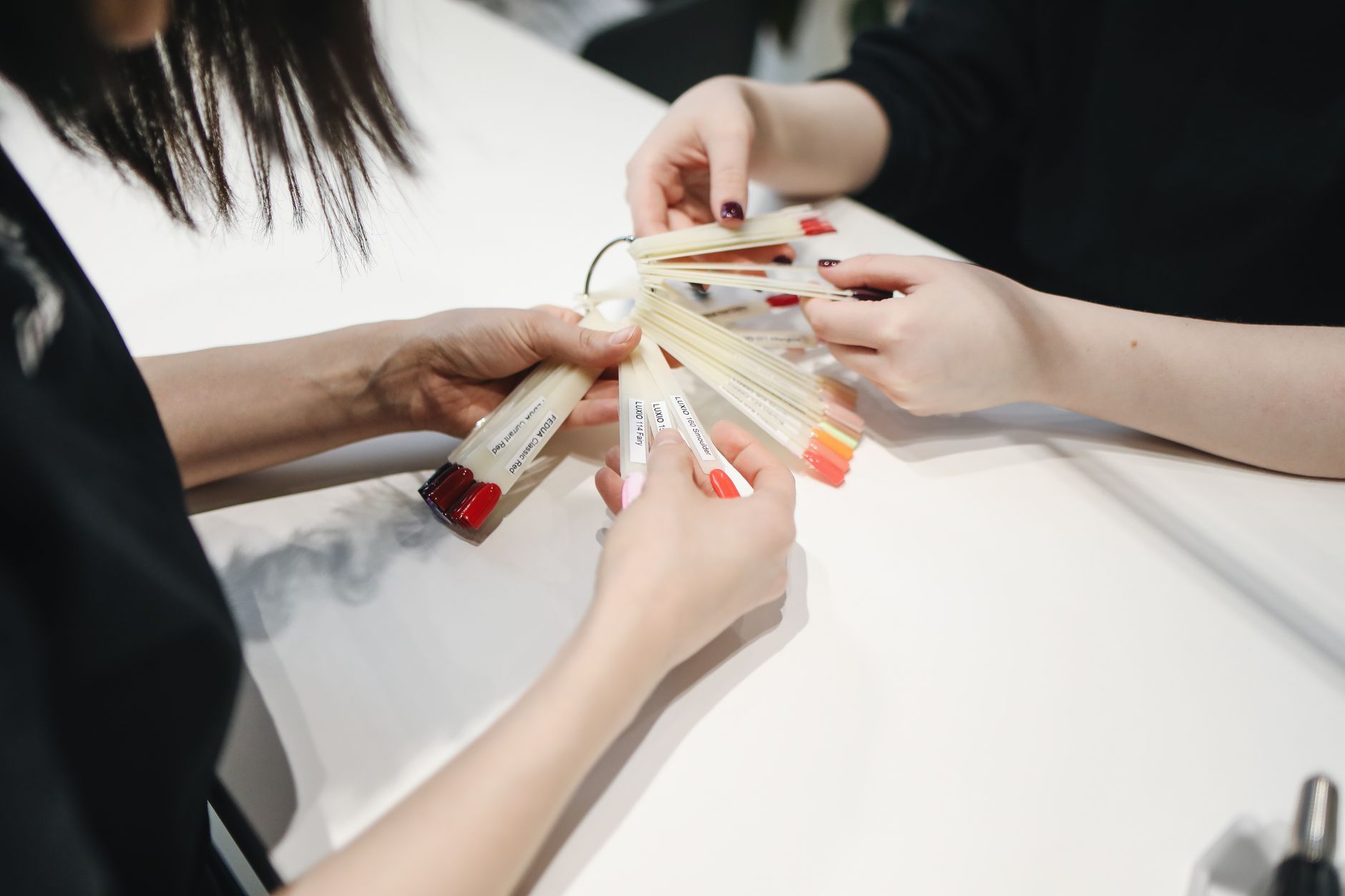 Dłonie wybierające kolory lakierów do paznokci w salonie manicure