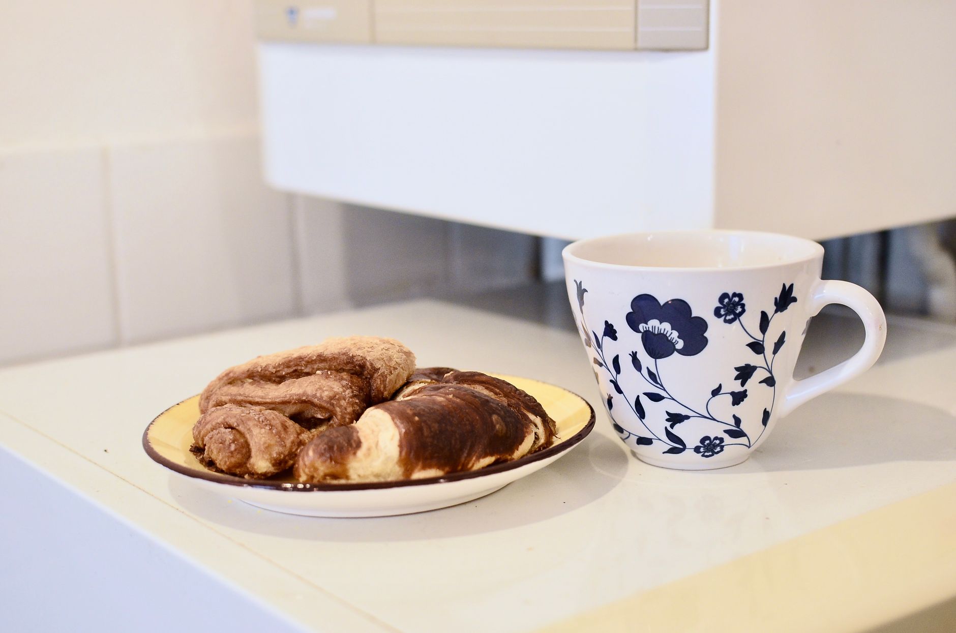 Świeże croissanty na talerzu obok kubka kawy w kuchni