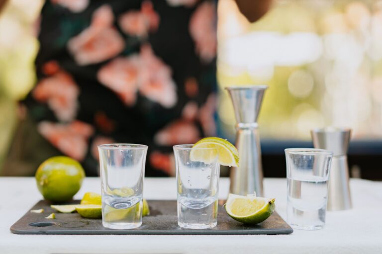Kieliszki do shotów z plasterkami limonki i miarki barmańskie w tle