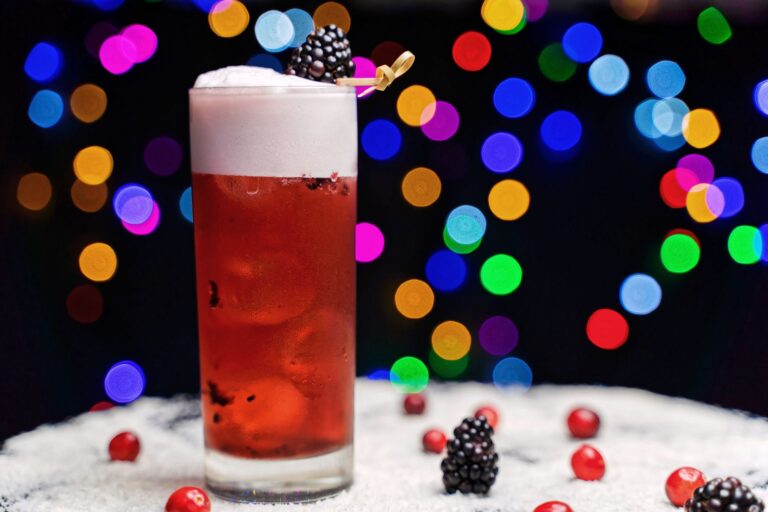 Kolorowy mocktail jagodowy z pianką na tle świątecznych światełek