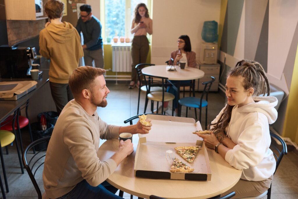Współpracownicy jedzą pizzę i piją kawę podczas przerwy w biurze
